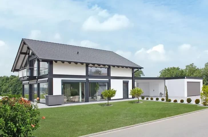 Modernes zwei Stockwerke Einfamilienhaus in Weiß mit dunklem Fachwerk und Garage auf großem Grundstück mit Rasen